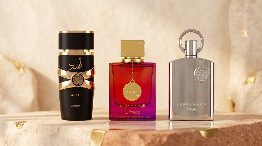 Lattafa Asad, Armaf Club de Nuit Untold and Afnan Supremacy Silver bottles on a warm cream and terracotta setting — affordable fragrance dupes